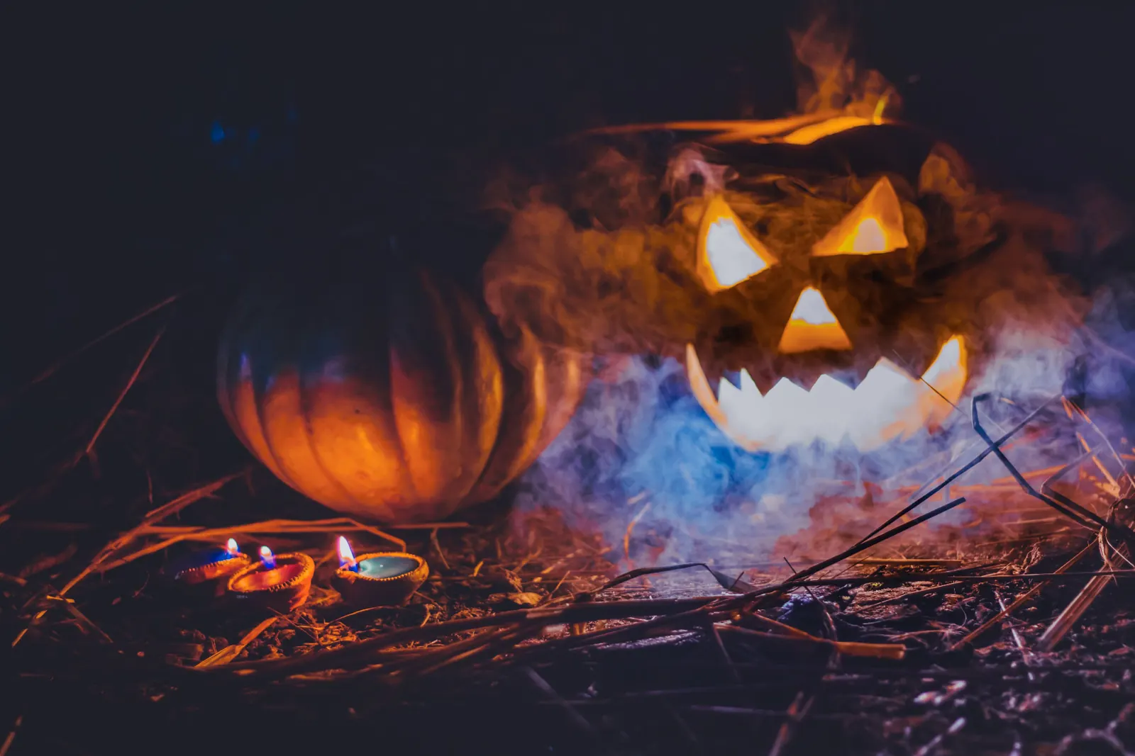 Seasonal atmosphere: a glowing jack-o'-lantern in fog beside small candles (stock photo, not Merlot House)