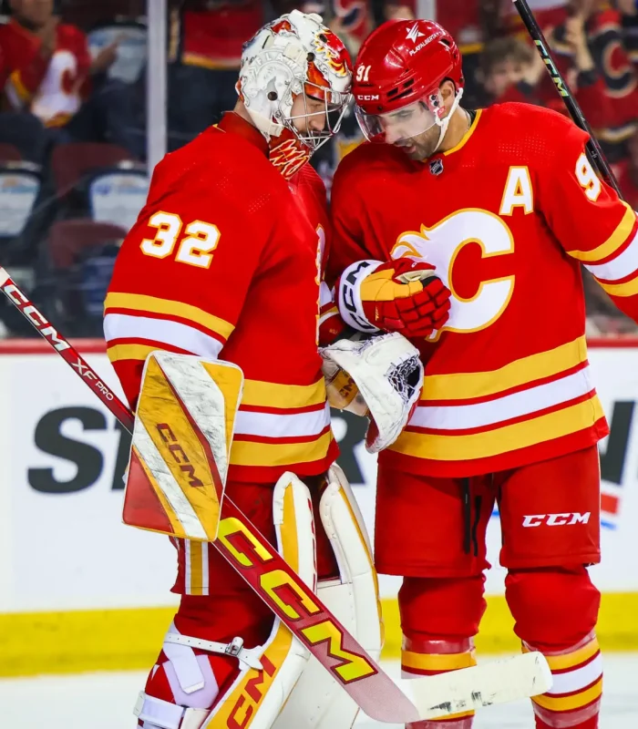Apr 18, 2024; Calgary, Alberta, CAN; Calgary Flames goaltender Dustin Wolf (32) and center Nazem Kadri (91) celebrates win against San Jose Sharks at Scotiabank Saddledome. Mandatory Credit: Sergei Belski-USA TODAY Sports